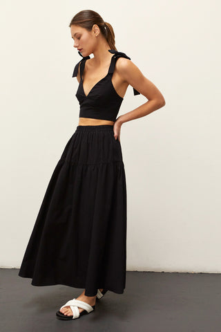 A woman wearing a black bow tie top two piece set.