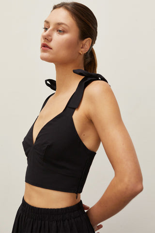 A woman wearing a black bow tie top two piece set.