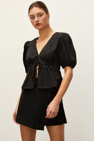 A woman wearing a black tiered puff short sleeve blouse.