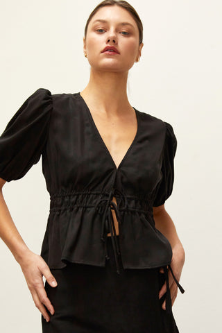A woman wearing a black tiered puff short sleeve blouse.