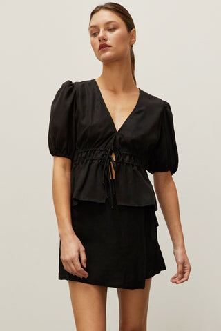 A woman wearing a black tiered puff short sleeve blouse.
