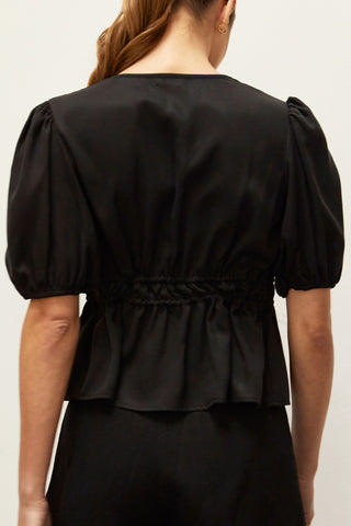A woman wearing a black tiered puff short sleeve blouse.
