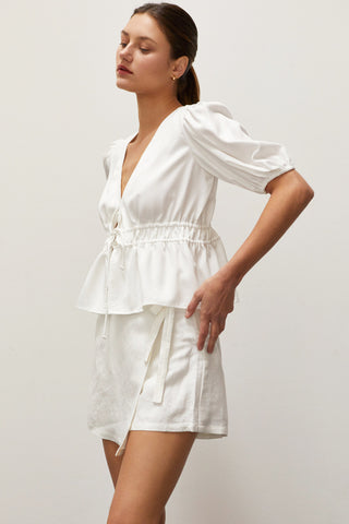 A woman wearing a white tiered puff short sleeve blouse.