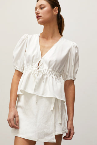 A woman wearing a white tiered puff short sleeve blouse.