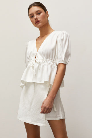 A woman wearing a white tiered puff short sleeve blouse.