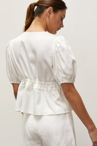 A woman wearing a white tiered puff short sleeve blouse.