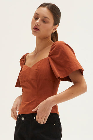 A woman wearing a rust backless with laced up straps top.