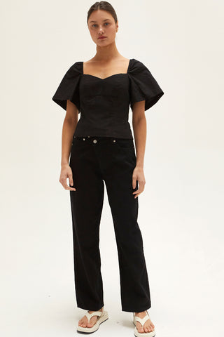 A woman wearing a black backless with laced up straps top.