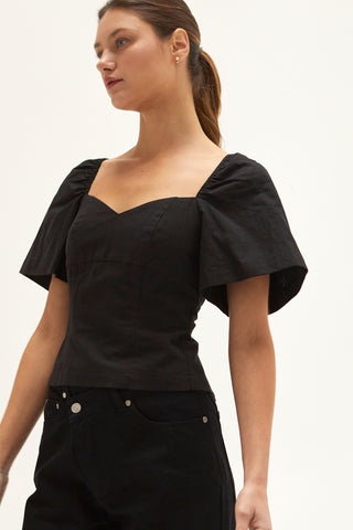 A woman wearing a black backless with laced up straps top.