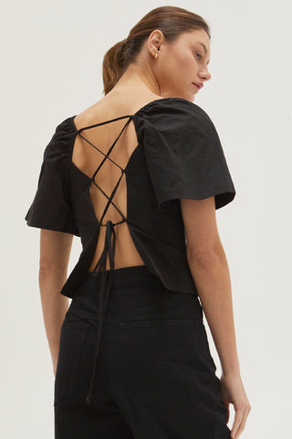A woman wearing a black backless with laced up straps top.