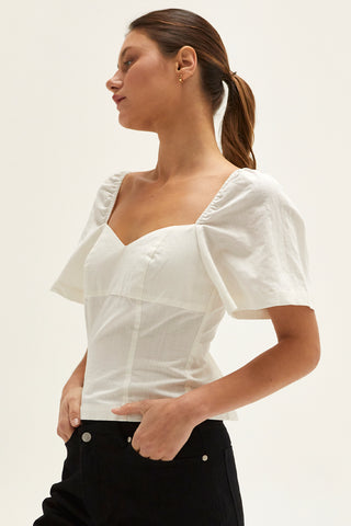 A woman wearing an ivory backless with laced up straps top.