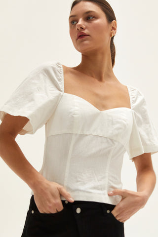 A woman wearing an ivory backless with laced up straps top.