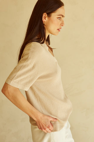 A woman wearing a taupe polo sweater top.