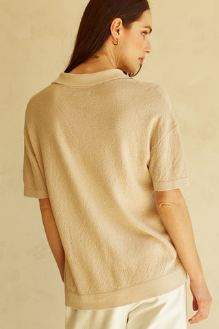 A woman wearing a taupe polo sweater top.