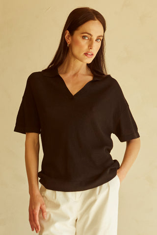 A woman wearing a black polo sweater top.