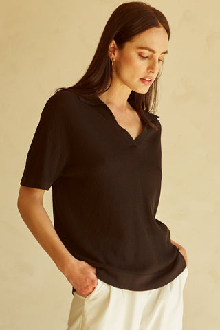 A woman wearing a black polo sweater top.