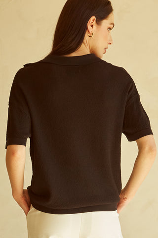 A woman wearing a black polo sweater top.