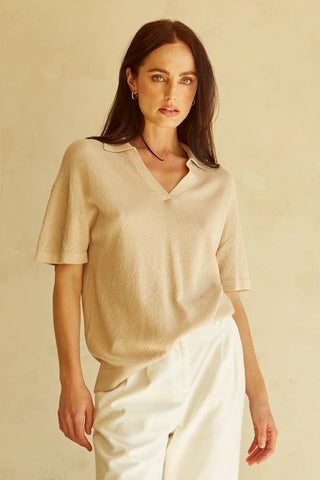 A woman wearing a taupe polo sweater top.