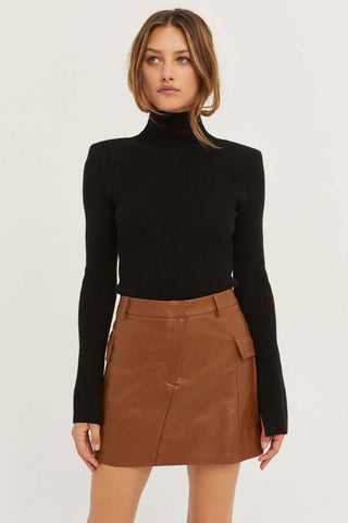 model wearing a black sweater and brown skirt