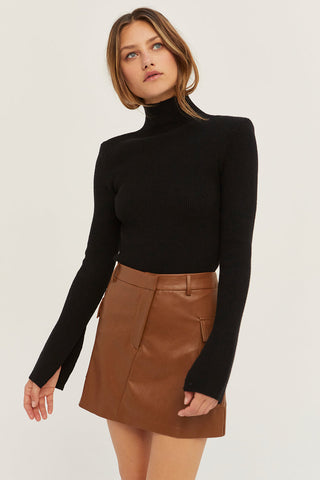 model wearing a black knit sweater and leather skirt