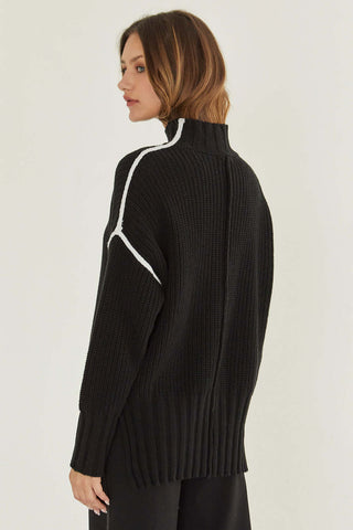 model wearing a black sweater with white seam contrast
