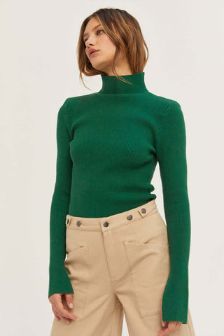 model wearing a green sweater and beige pants